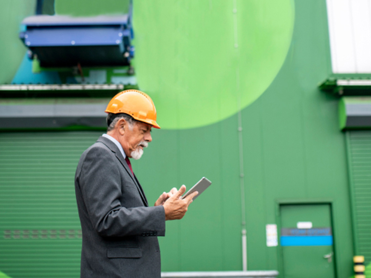 Man wearing yellow hard hat holding a tablet